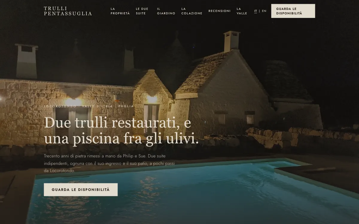 Il sito di Trulli Pentassuglia su un computer: due trulli illuminati di sera e la piscina fra gli ulivi